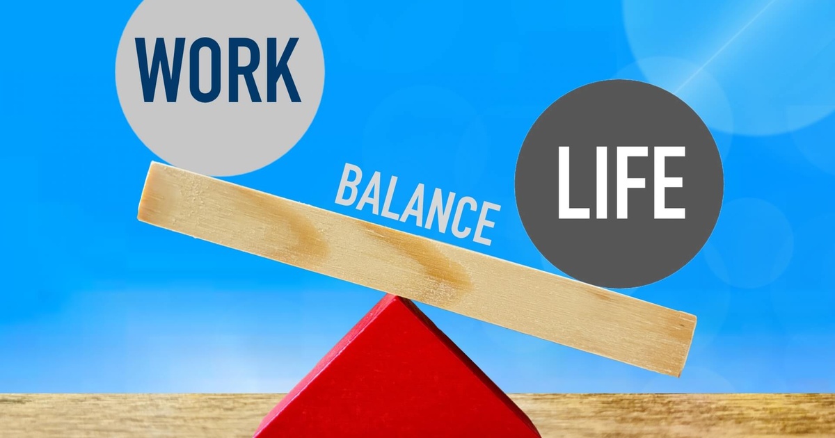 青空を背景に、赤い三角の支点に木の棒が置かれ、左にWORK、右にLIFEの文字が入った円が乗り、中央にBALANCEと記されたワークライフバランスを表現した写真