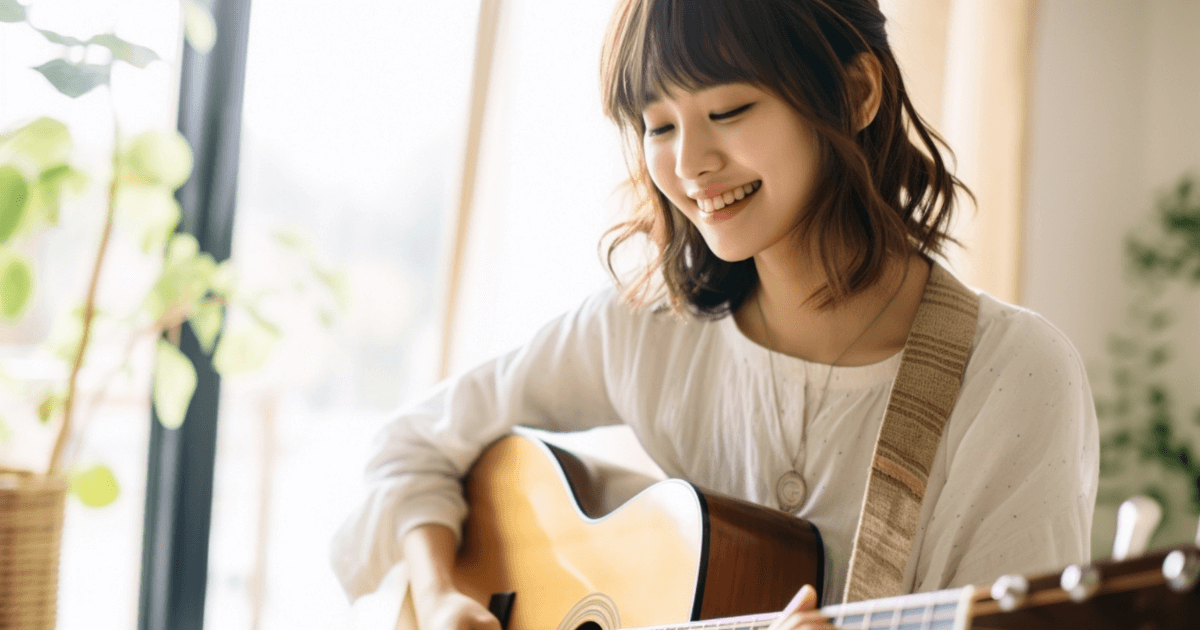 明るい部屋で笑顔でアコースティックギターを演奏する女性。集合住宅での演奏を楽しむイメージ。