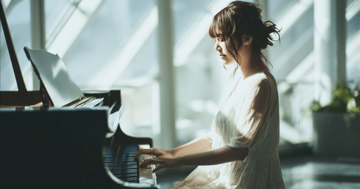 静かな光の中でピアノを弾く女性の写真。快適な演奏環境をイメージしたまとめ用イメージ。