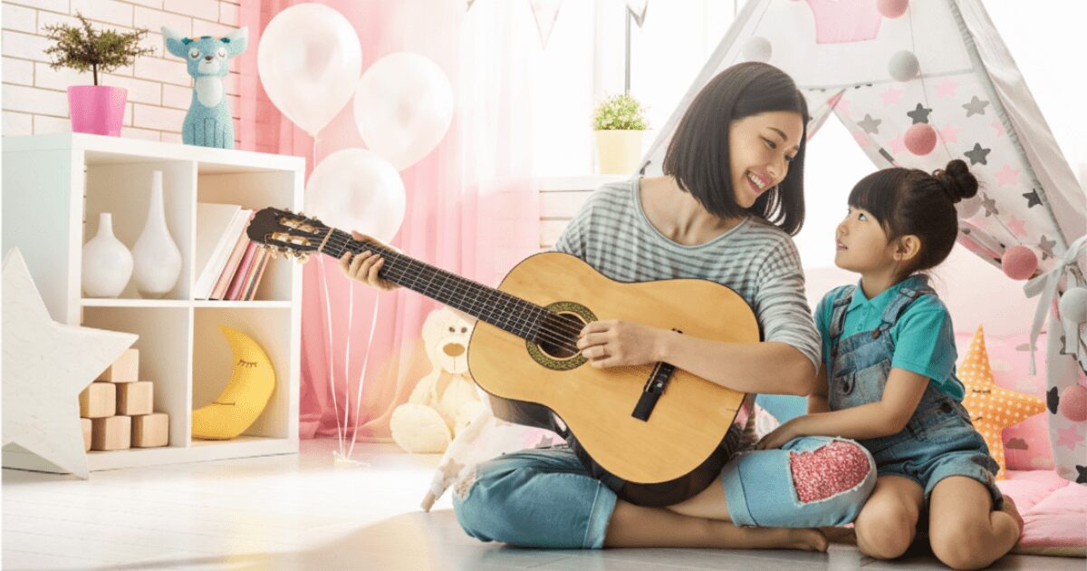 母と子どもが室内でギターを楽しむ様子。親子で音楽を楽しむイメージ写真。